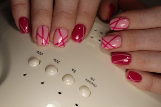 Stylish trendy female manicure. Beautiful young woman's hands on pink