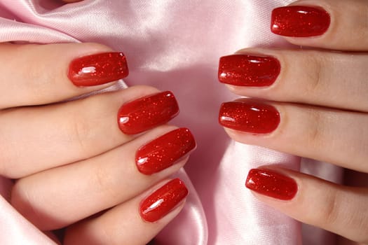 Hands of a woman with red manicure are on a towel