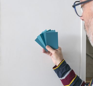 a man with different color swatches for determining the right color of paint on a wall