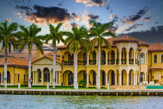 A large mansion on a canal with palm trees at christmas