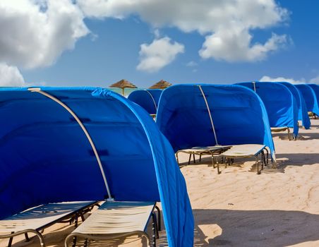 Blue Beach Shelters and Umbrellas on a beach on a cloudy day