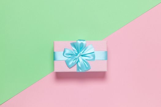 Pink gift box with blue bow on pastel two-color background pink and green, copy space, flat lay. March 8, February 14, birthday, St. Valentine's, Mother's, Women's day celebration concept. Horizontal.