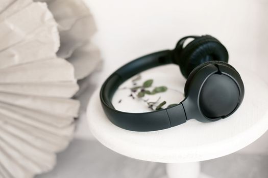 Black headphones on a white stand.