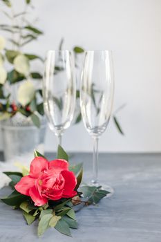 Composition with glass for champagne. Flowers and hearts on grey concrete background