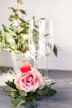 Composition with glass for champagne. Flowers and hearts on grey concrete background