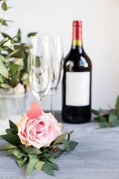 Composition with glass, flowers and bottle of vine on grey concrete background