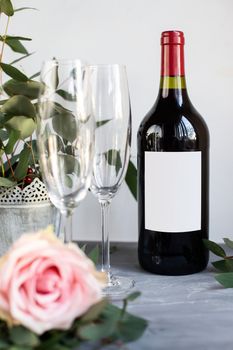 Composition with glass, flowers and bottle of vine on grey concrete background