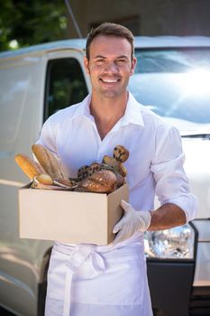 Portrait of delivery man holding parcel standing in front of his van
