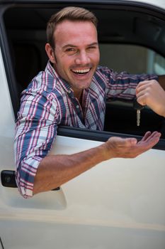 Portrait of young man receiving car keys in his car
