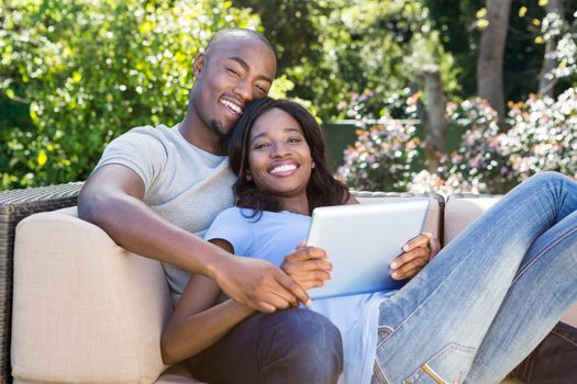 Portrait of young couple relaxing on the sofa and using digital tablet in the park