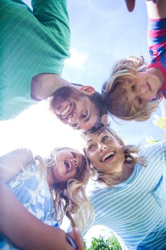 Low angle view of happy family forming huddle in yard 