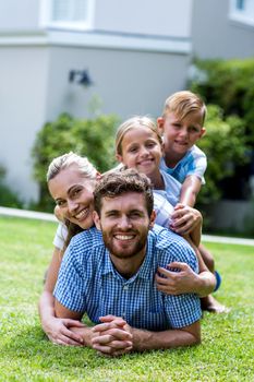 Happy family lying on top of each other in yard 