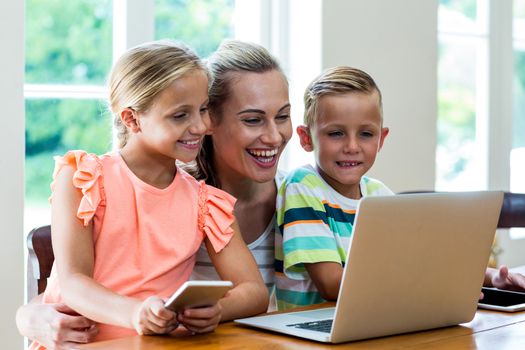 Smiling mother and children looking at laptop in home 