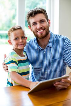 Portrait of smiling father and son with digital tablet at home 