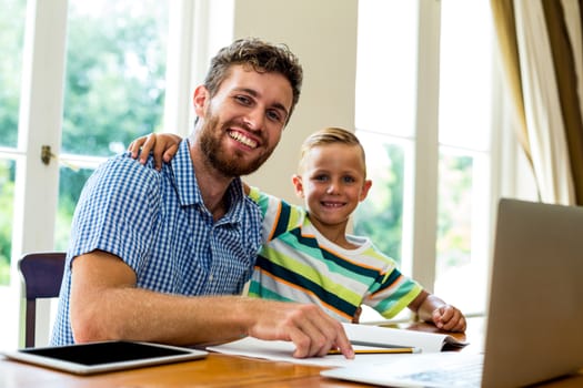 Portrait of smiling father and son sitting at table 