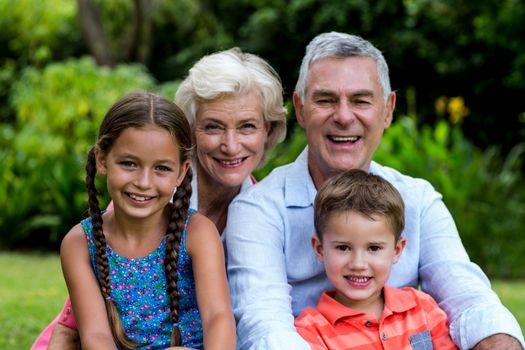 Portrait of smiling grandparents with grandchildren at yard 