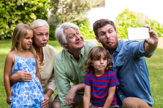 Happy family making face while taking selfie with family while sitting in yard