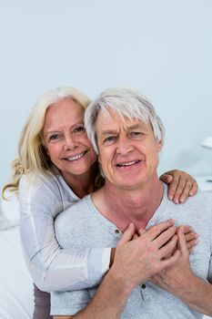Portrait of smiling senior couple hugging in bedroom at home