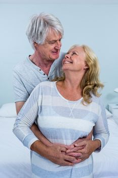 Happy senior couple hugging in bedroom at home