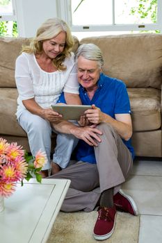 High angle view of senior couple using digital tablet in living room at home