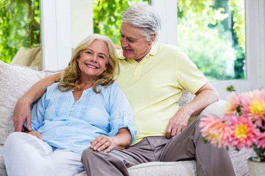 Romantic senior couple sitting on sofa in living room at home