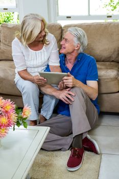 High angle view of happy senior couple using digital tablet in living room at home