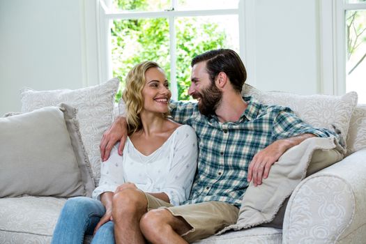 Romantic young couple looking at each other on sofa