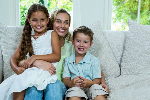 Portrait of cheerful mother with daughter and son on sofa at home