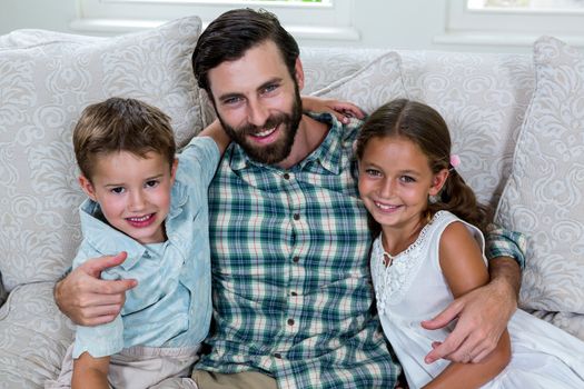 Portrait of happy father with children on sofa at home
