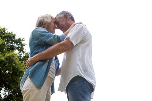 Romantic senior couple embracing in back yard against clear sky