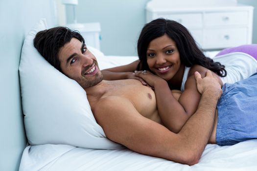 Portrait of romantic couple lying together on bed in bedroom