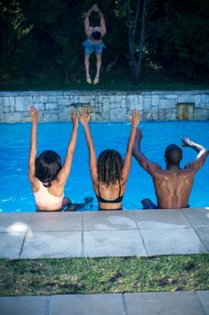 Rear view of friends enjoying their holiday at a swimming pool