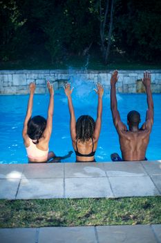 Rear view of friends enjoying their holiday at a swimming pool