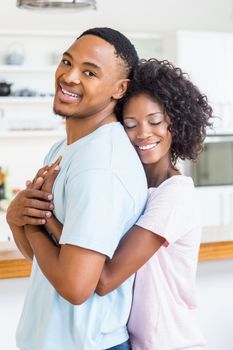 Happy young couple embracing in kitchen at home