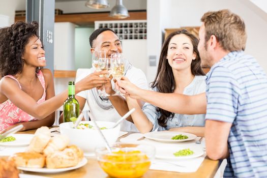 Friends toasting wine glasses while having a meal at dining table