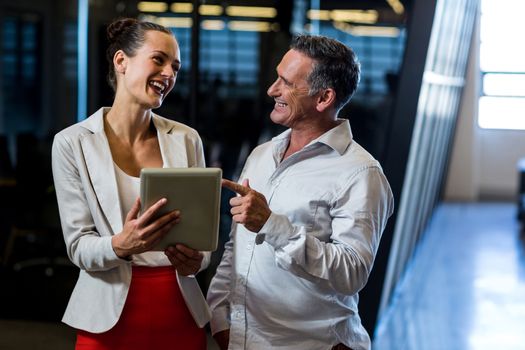 Businessman and businesswoman discuss using digital tablet in the office