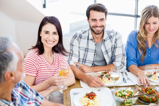 Portrait of woman sitting with friends at dinning table while having meal