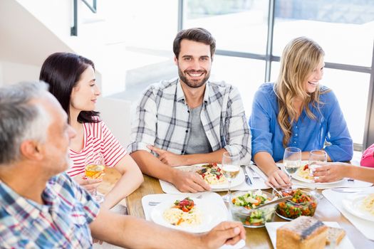 Portrait of man sitting with friends at dinning table while having meal