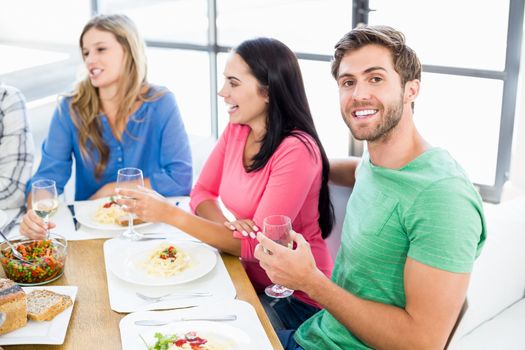 Portrait of man sitting with friends at dinning table while having meal