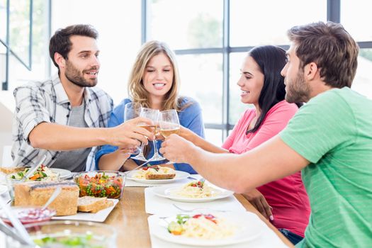 Friends toasting wine glasses while having a meal at dining table