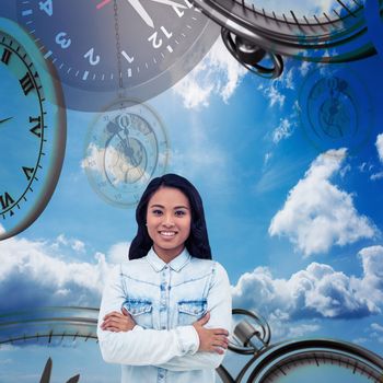 Asian woman with arms crossed smiling against blue sky