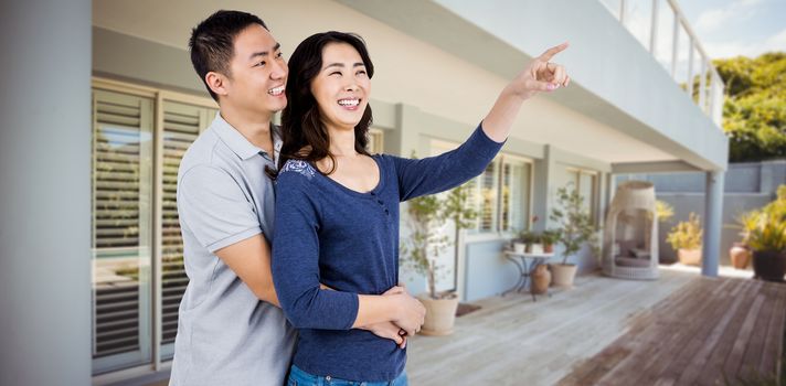 Happy couple with woman pointing up against stylish outdoor patio area