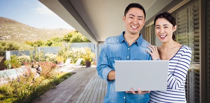 Portrait of couple using laptop against stylish outdoor patio area