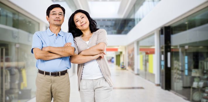 Smiling couple with arms folded against interior of modern shopping mall