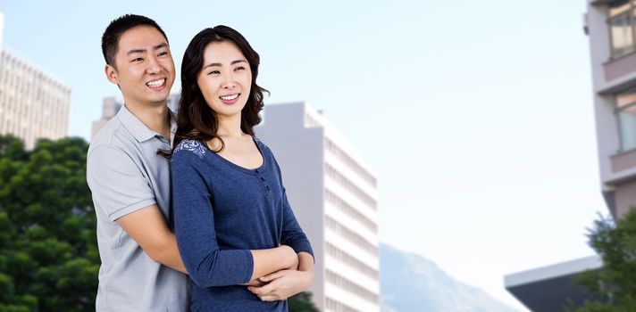 Cheerful couple embracing against low angle view of city buildings