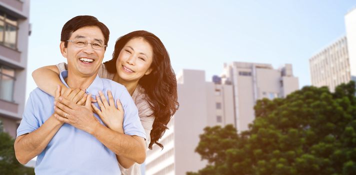 Smiling couple holding each other against low angle view of city buildings