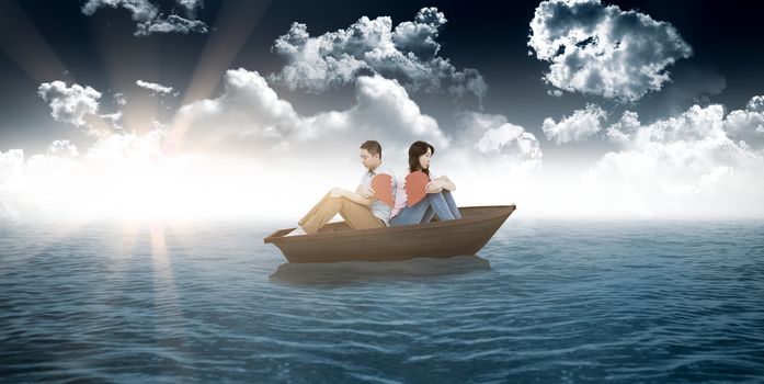 Sad couple holding broken heart pieces against small boat in open sea
