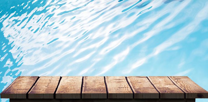 Wooden floor against ripples on blue swimming pool