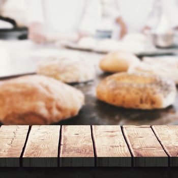 Wooden desk against co-workers making bagels and bread together