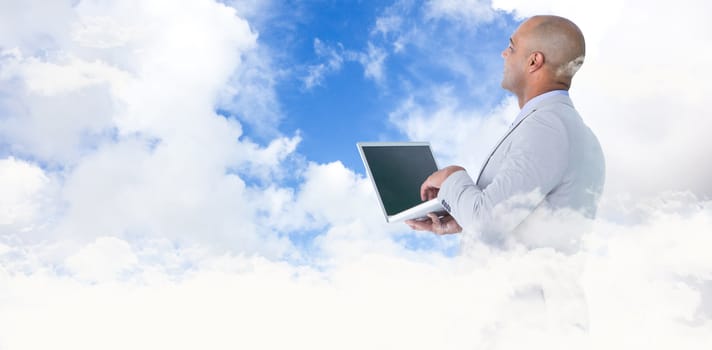 Businessman using laptop against blue sky with white clouds